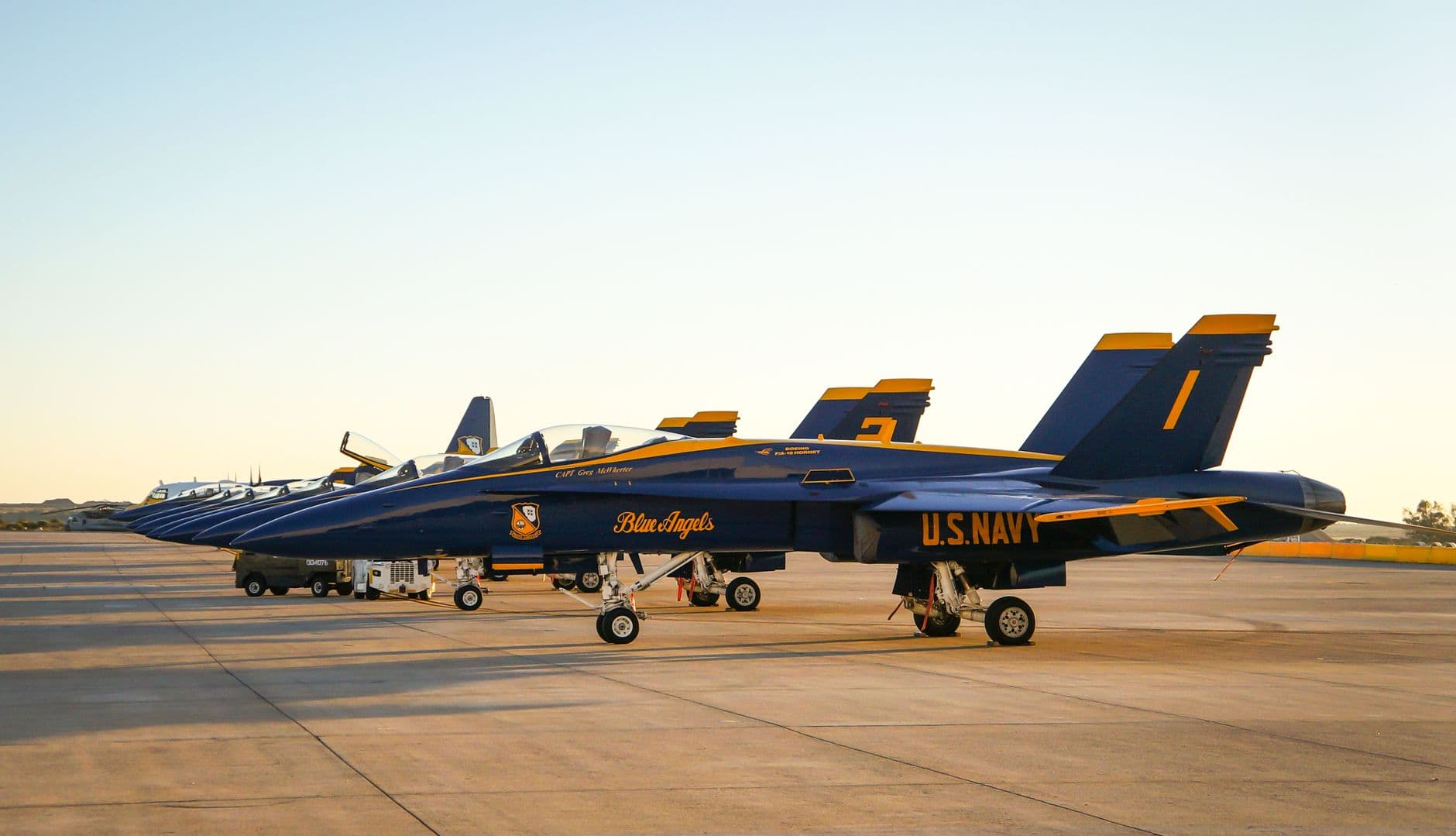 US Navy Blue Angels fighter jets lined up on San Diego runway at sunset.